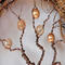 twisted brown aluminum branches are decorated with textured, shiny, sand, dirt, earth color beads